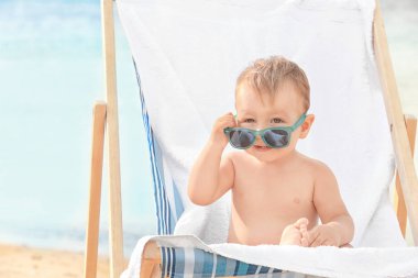 Küçük çocuk, sahil plaj sandalye üzerinde oturan