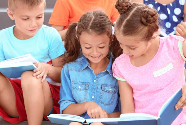 Lindos niños pequeños leyendo libros al aire libre —  Fotos de Stock