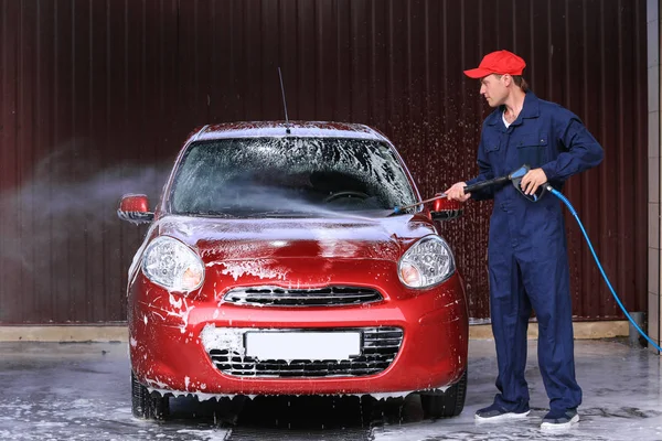 Hombre de limpieza de automóviles con agua de alta presión en el lavado de coches — Foto de Stock