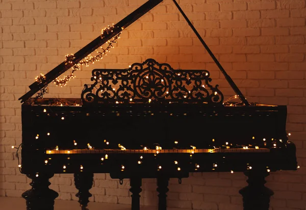 Пианино с рождественскими огнями в пустой комнате — стоковое фото