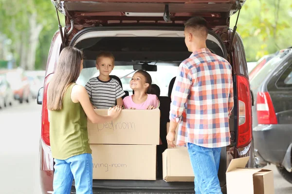 Familia feliz con cajas cerca del coche, al aire libre — Foto de Stock