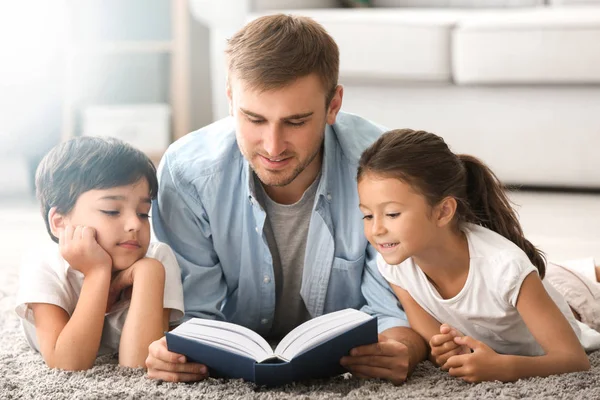 Le jeune homme et ses petits enfants lisent un livre à la maison — Photo