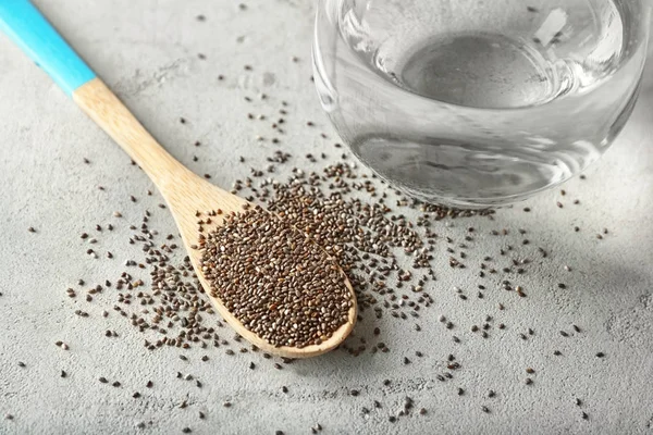 Spoon with chia seeds and glass of water on table — Stock Photo, Image