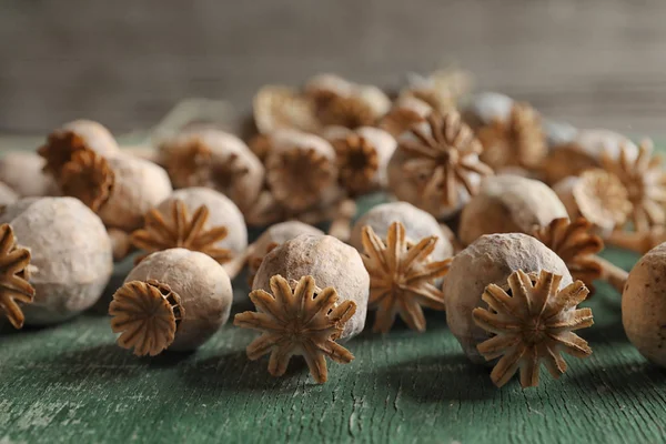 Poppy heads on green wooden table, closeup — Stock Photo, Image