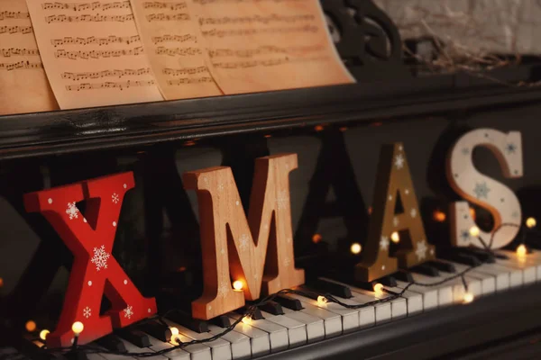Teclado para piano con palabra XMAS y luces navideñas —  Fotos de Stock