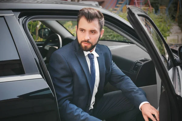 Un bell'uomo in giacca e cravatta che scende dalla macchina — Foto Stock