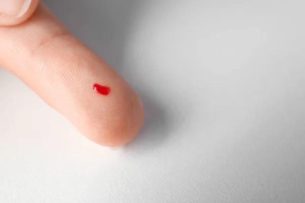 Finger of woman with blood drop — Stock Photo, Image