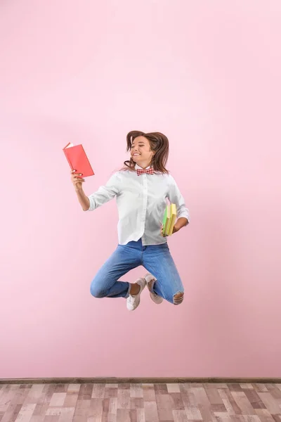 Genç kız renk duvarının yakınında kitaplarla atlama — Stok fotoğraf