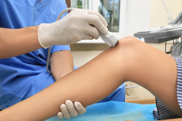 Médecin effectuant une échographie du genou du patient en clinique — Photo