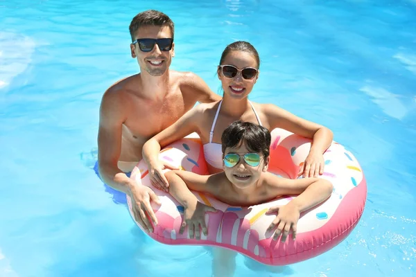 Família feliz com donut inflável na piscina — Fotografia de Stock