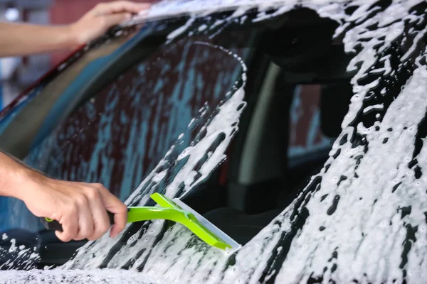 Hombre limpiando el parabrisas del automóvil con la escobilla en el lavado de coches —  Fotos de Stock