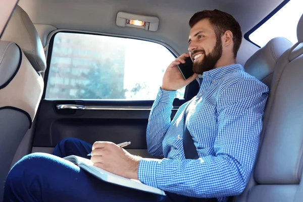 Przystojny mężczyzna z smartphone na tylnym siedzeniu samochodu — Zdjęcie stockowe