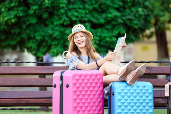 Schöne junge Touristin mit Karte sitzt auf Bank im Park — Stockfoto