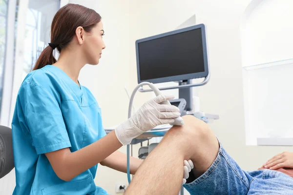 Médico realizando ecografía de rodilla del paciente en clínica —  Fotos de Stock