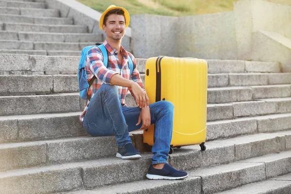 Młody człowiek z walizką, siedząc na schodach — Zdjęcie stockowe