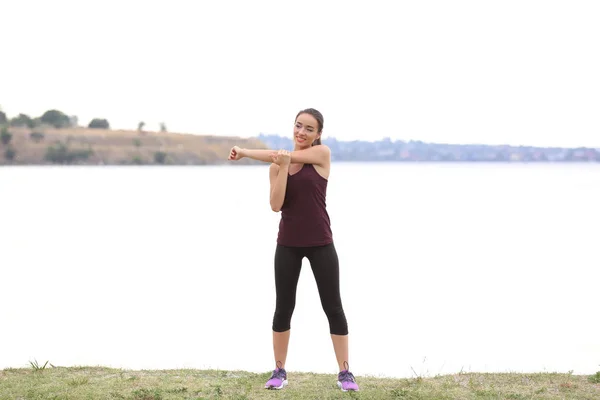 Joven mujer deportiva haciendo ejercicio en la orilla del río —  Fotos de Stock