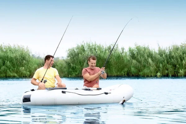 Dois homens que pescam do barco inflável no rio — Fotografia de Stock