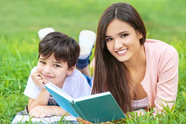 若い女性と彼女の幼い息子を公園で読書 — ストック写真