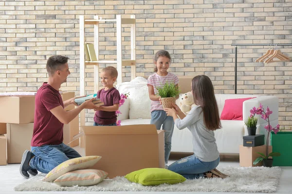 Happy family unpacking cardboard boxes in room at new house