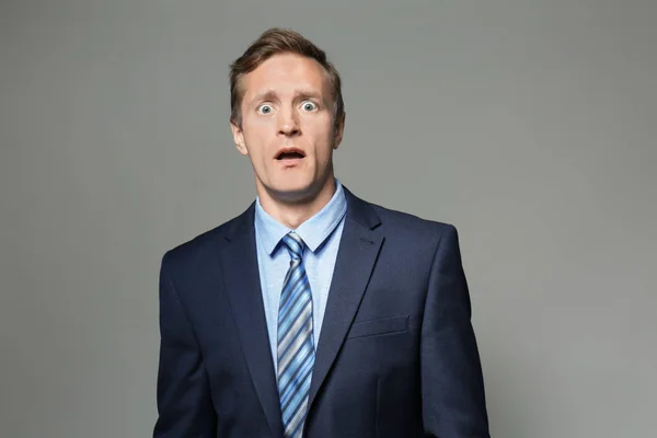 Emotional man in suit on grey background — Stock Photo, Image