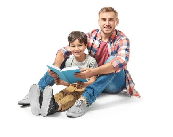 Молодий чоловік і його маленький син читають книгу на білому тлі — стокове фото
