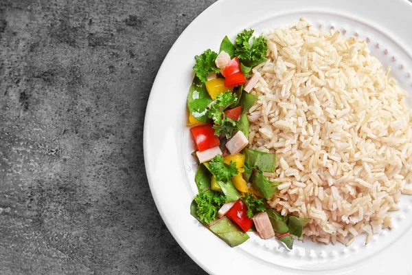 Prato com delicioso arroz integral e legumes na mesa — Fotografia de Stock