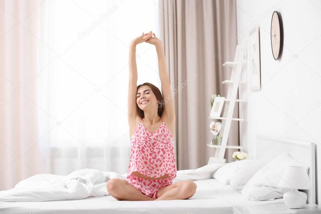 Young woman stretching on bed in morning