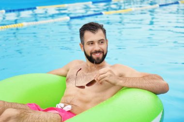Yakışıklı delikanlı şişme halka mavi yüzme havuzunda rahatlatıcı ile