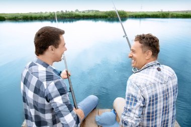 İki adam nehirde iskelede balık tutuyor.