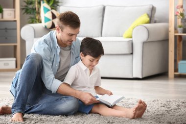 Genç adam ve küçük oğlu evde kitap okuma