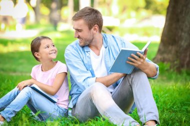Genç adam ve küçük kızı Park kitap okuma
