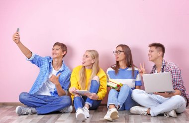 Renk duvarının yakınında katta otururken selfie alarak gençler