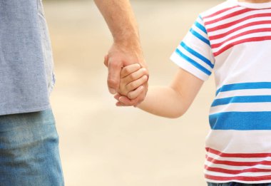 Çocuk babasının elini açık havada tutarak