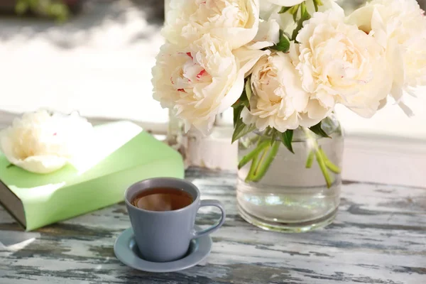 Tasse Tee und Vase mit Pfingstrosenblüten — Stockfoto