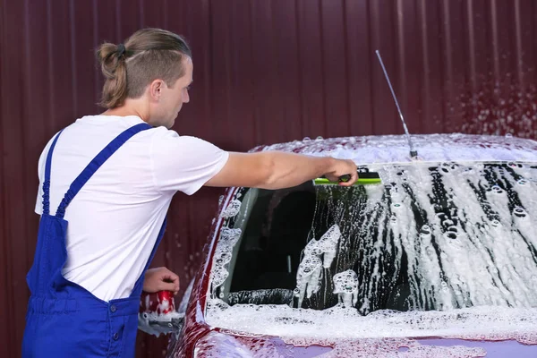 Man cleaning automobile windscreen with squeegee at car wash — Stock Photo, Image