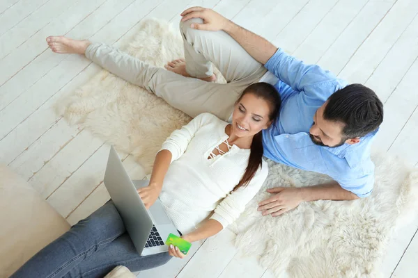 Pareja joven con laptop y tarjeta de crédito en casa. Concepto de compras por Internet —  Fotos de Stock