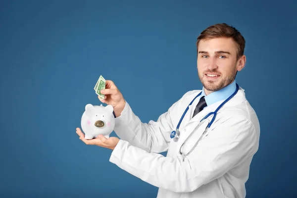 Young doctor with piggy bank — Stock Photo, Image