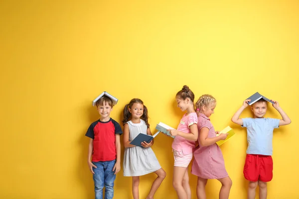 Lindos niños pequeños con libros sobre fondo de color — Foto de Stock