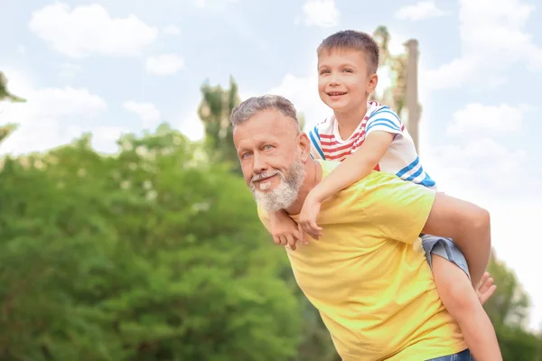 Милый мальчик веселится с дедушкой на открытом воздухе — стоковое фото