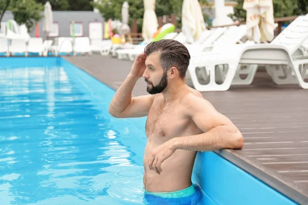 Przystojny młody mężczyzna relaksujący w niebieski basen — Zdjęcie stockowe