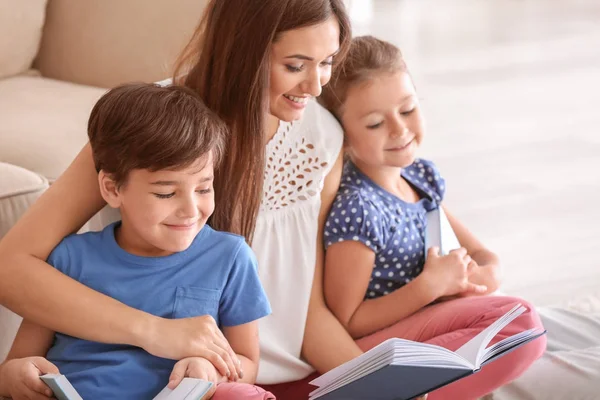 Jeune femme et ses petits enfants lisant des livres à la maison — Photo