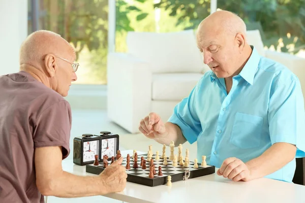 Elderly men playing chess at home — Stock Photo, Image