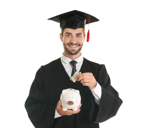 Young graduate with piggy bank on white background — Stock Photo, Image
