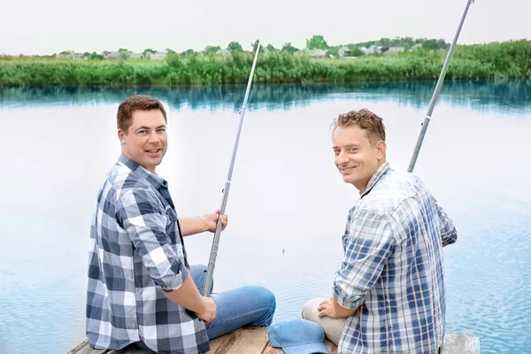 Dos hombres pescando desde el muelle en el río — Foto de Stock