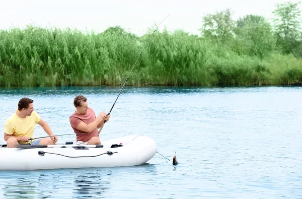 Dos hombres que pescan del barco inflable en río — Foto de Stock