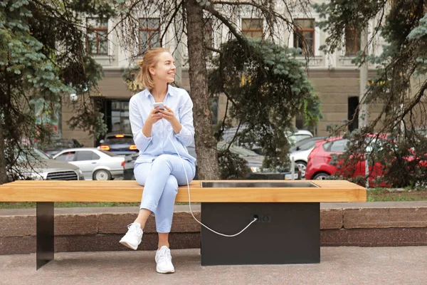 Young woman charging mobile phone