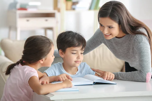 Jonge vrouw en haar lieve kinderen thuis boeken lezen — Stockfoto