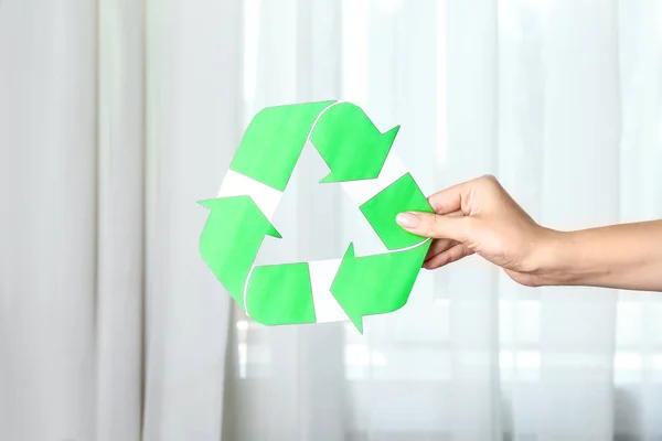 Mujer sosteniendo símbolo de reciclaje en interiores —  Fotos de Stock
