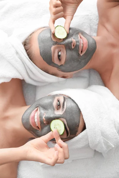 Jovens mulheres com máscaras faciais e fatias de pepino no salão de spa — Fotografia de Stock