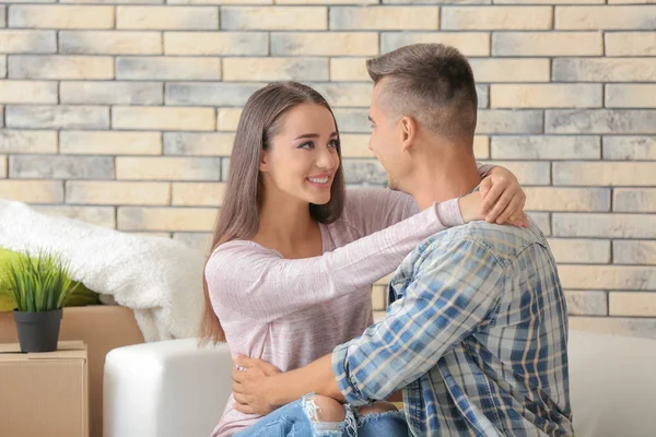 Unga lyckliga paret sitter på soffan i rummet på nya hem — Stockfoto